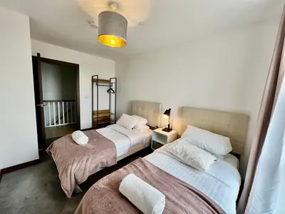 a bedroom with two beds and a lamp in it at Walnut Tree Penthouse Next to Train Station in Cambridge
