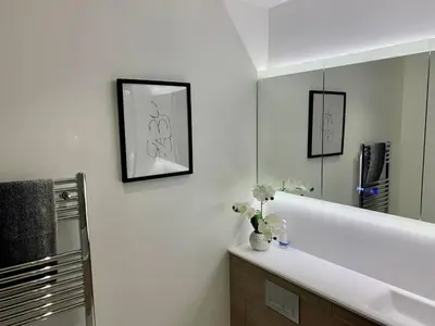 a bathroom with a white sink and a mirror at Walnut Tree Penthouse Next to Train Station in Cambridge