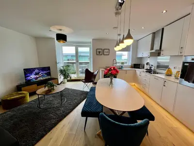 a living room with a table and a kitchen at Walnut Tree Penthouse Next to Train Station in Cambridge