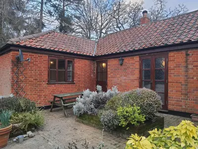 a brick house with a bench in a garden at Cosy Barn Conversion 3BR (4 pax), Quiet, Close to Pin Mill in Chelmondiston