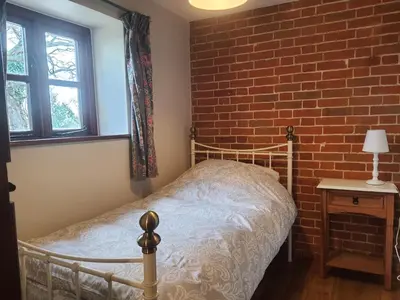 a bed in a room with a brick wall at Cosy Barn Conversion 3BR (4 pax), Quiet, Close to Pin Mill in Chelmondiston