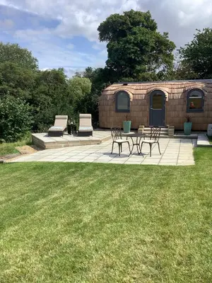 a brick building with chairs and a table in the grass at SkyFall in Grundisburgh