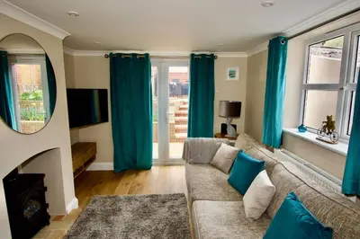 a living room with blue curtains and a couch at Cottage in Framlingham in Framlingham