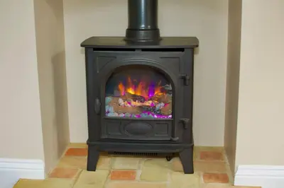 a black stove with a fire in a room at Cottage in Framlingham in Framlingham