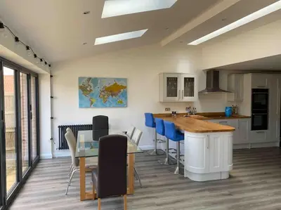 a kitchen with a glass table and blue chairs at Rockhopper Cottage, Waldringfield in Woodbridge