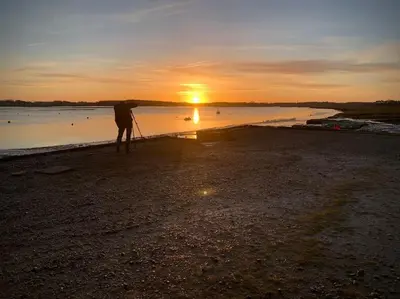 a person standing on the beach watching the sunset at Rockhopper Cottage, Waldringfield in Woodbridge