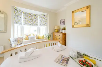 a bedroom with two beds and a window with a mirror at Shearwater Cottage in Aldeburgh