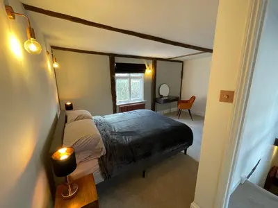 a bedroom with a bed and a table with a lamp at Abbey Gardens Cottage in Bury Saint Edmunds