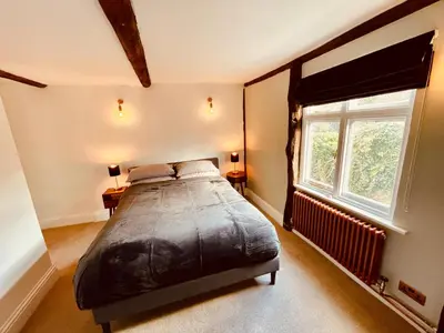 a bedroom with a large bed and a window at Abbey Gardens Cottage in Bury Saint Edmunds