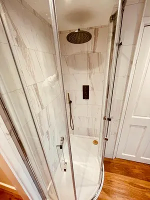 a shower with a glass door in a bathroom at Abbey Gardens Cottage in Bury Saint Edmunds