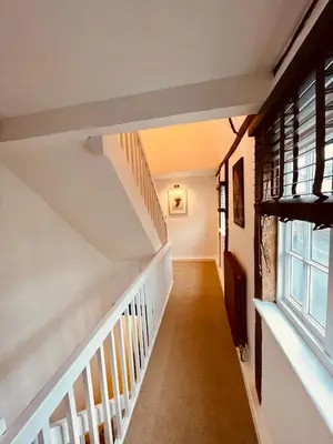 a hallway with stairs in a house with a window at Abbey Gardens Cottage in Bury Saint Edmunds