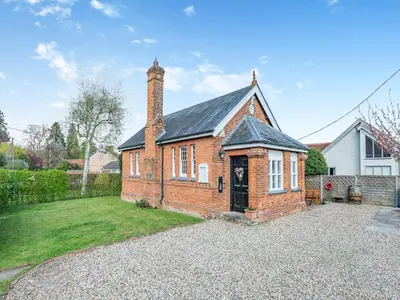 a brick house with a chimney on top of a yard at The Old Parish Hall in Quendon
