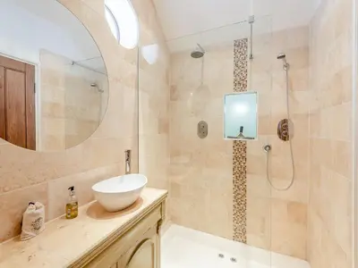 a bathroom with a sink and a shower with a mirror at The Old Parish Hall in Quendon