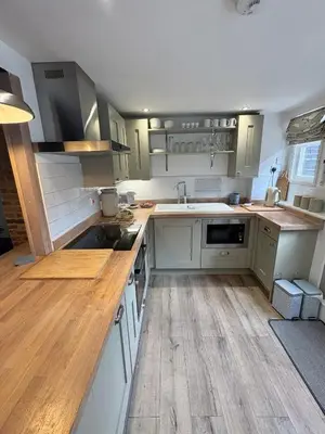 a kitchen with white cabinets and a wooden floor at Stylish Town House in Medieval Grid in Bury Saint Edmunds