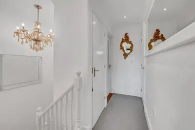 a white hallway with a chandelier and white walls at Stylish 3 bedroom townhouse for 5 guests, set in the medieval grid with off street parking in Bury Saint Edmunds