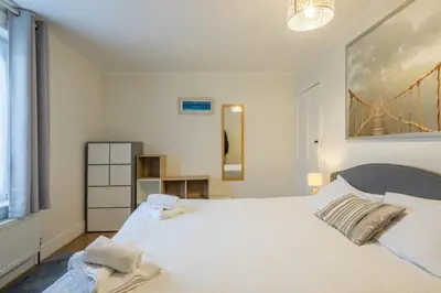 a bedroom with a white bed with a painting on the wall at 4 Bed Central Home - Perfect Location with Parking in Cambridge