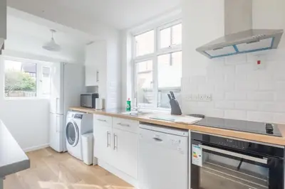 a white kitchen with a sink and a dishwasher at Charming Central Family Home in Cambridge
