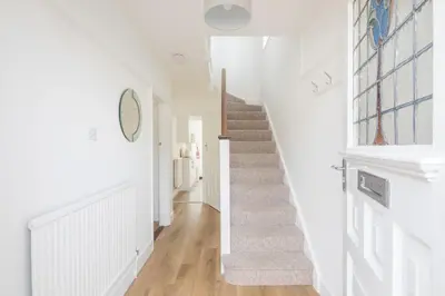 a hallway with white walls and a staircase with white floors at Charming Central Family Home in Cambridge