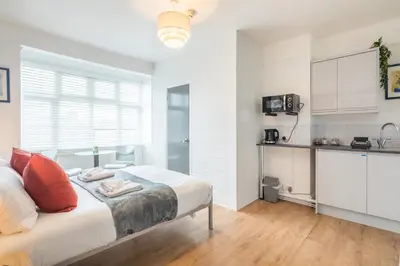 a white bedroom with a bed and a kitchen at The Modern Cambridge Studio 4 in Cambridge