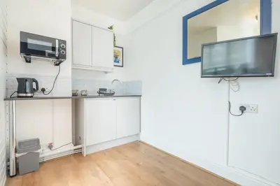 a kitchen with white cabinets and a tv on the wall at The Modern Cambridge Studio 4 in Cambridge