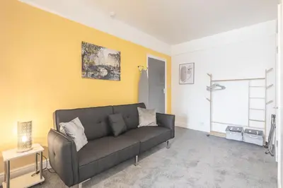 a living room with a couch and a yellow wall at The Modern Cambridge Studio 5 in Cambridge