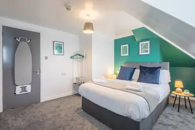 a bedroom with a large bed with a green wall at The Modern Cambridge Studio 7 in Cambridge