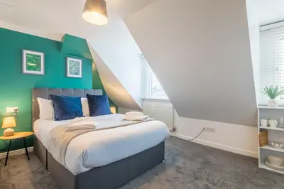 a bedroom with a bed with blue and green walls at The Modern Cambridge Studio 7 in Cambridge