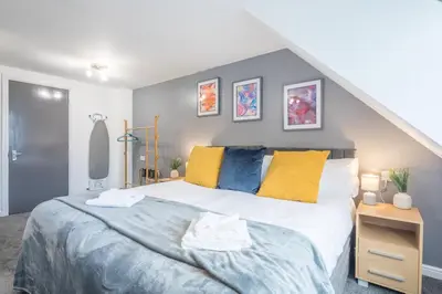 a bedroom with a large bed with yellow and blue pillows at The Modern Cambridge Studio 8 in Cambridge