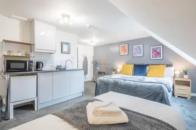 a bedroom with two beds and a kitchen in a room at The Modern Cambridge Studio 8 in Cambridge