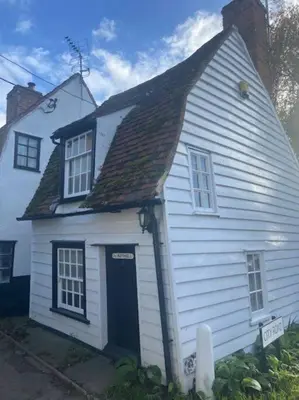 a small white house with a black door at The Nutshell in West Mersea