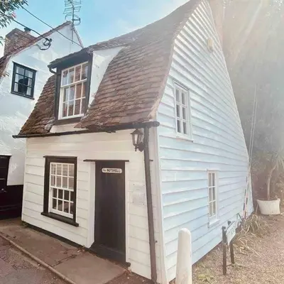 a small white house with a black door at The Nutshell in West Mersea