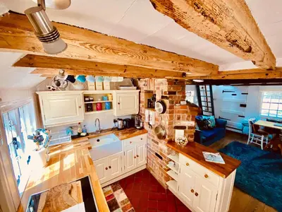 a kitchen with white cabinets and a blue couch at The Nutshell in West Mersea