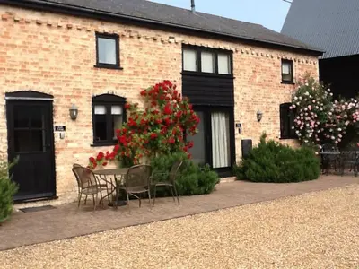 a brick house with a table and chairs and flowers at Pretty Cottage In Charming Peaceful Village - Easy Commute to Cambridge - Cambridge Homehost in Cambridge