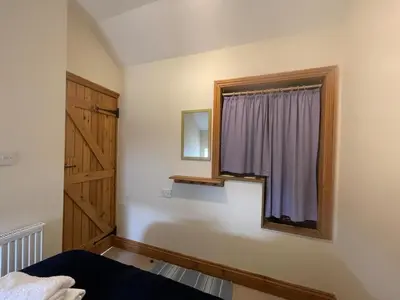 a bedroom with a window and a wooden door at Pretty Cottage In Charming Peaceful Village - Easy Commute to Cambridge - Cambridge Homehost in Cambridge