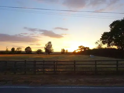 a fence in a field with the sunset in the background at Pretty Cottage In Charming Peaceful Village - Easy Commute to Cambridge - Cambridge Homehost in Cambridge