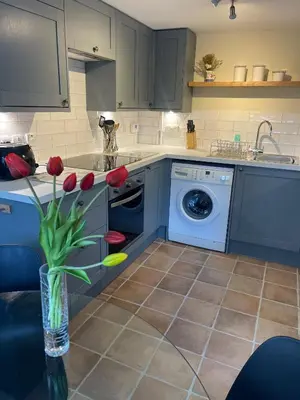 a kitchen with a washing machine and red tulips in a vase at Pretty Cottage In Charming Peaceful Village - Easy Commute to Cambridge - Cambridge Homehost in Cambridge