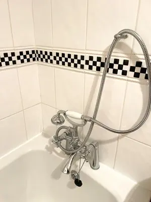 a bath tub with a shower head in a bathroom at Pretty Cottage in peaceful village location close To Cambridge in Cambridge