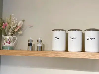 a shelf with three coffee cans on it at Pretty Cottage in peaceful village location close To Cambridge in Cambridge
