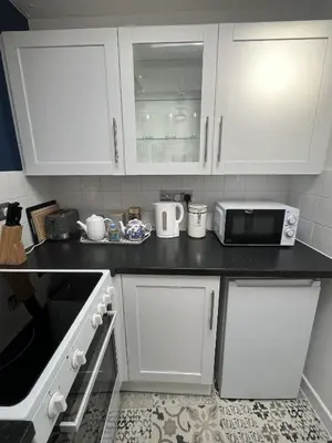 a kitchen with white cabinets and a microwave at Windmill Cottage in Ely