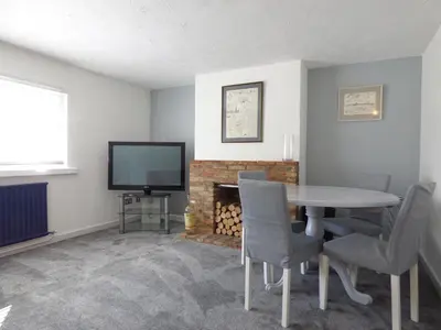 a dining room with a table and a tv and a fireplace at Windmill Cottage in Ely