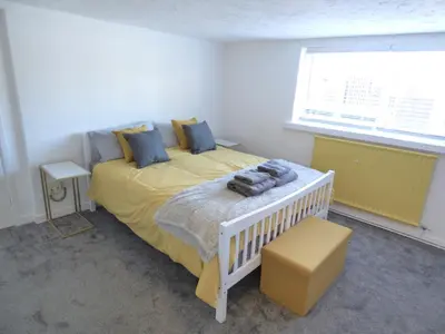 a bedroom with a bed with a yellow blanket and a window at Windmill Cottage in Ely