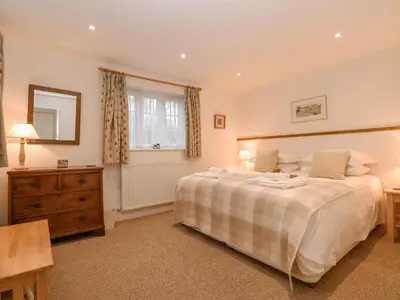 a bedroom with a bed and a dresser and a window at Valley Farm Cottage in Woodbridge