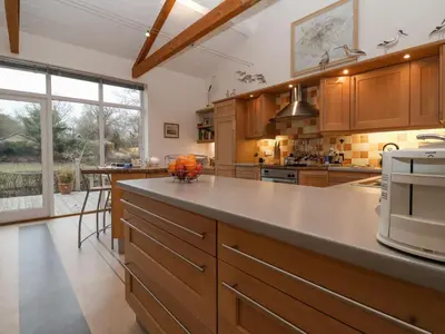 a large kitchen with wooden cabinets and a large island at Valley Farm Cottage in Woodbridge