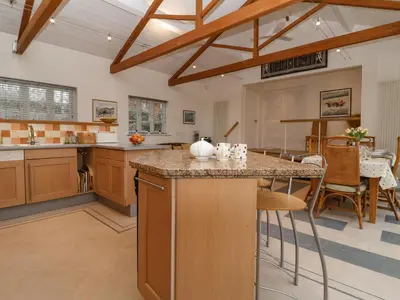 a large kitchen with wooden cabinets and a large island at Valley Farm Cottage in Woodbridge