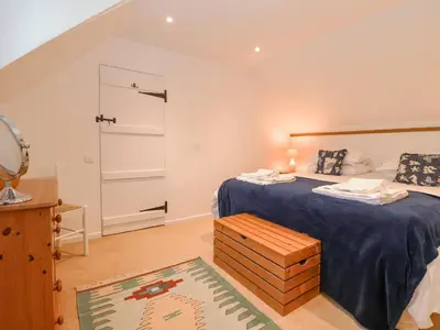a bedroom with a large bed with a blue blanket at Valley Farm Cottage in Woodbridge