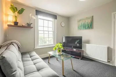 a living room with a couch and a table and a tv at Cambridge 3 bedroom flat with private parking in Cambridge