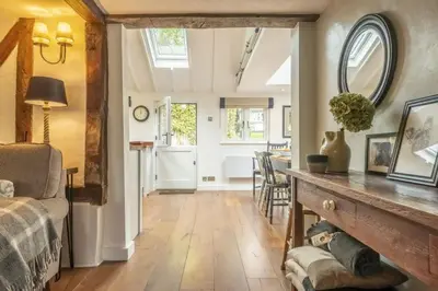 a living room with a bed and a table with a mirror at Well Green Cottage in Wenhaston