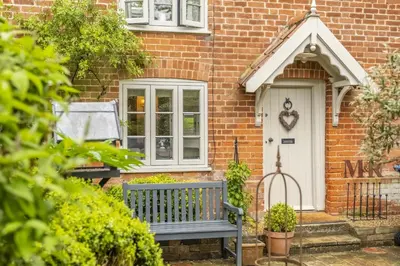 a brick house with a bench in front of a door at Well Green Cottage in Wenhaston