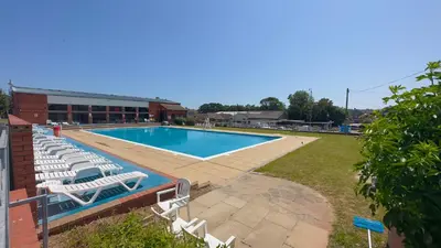 a swimming pool with lounge chairs next to a building at Freedom House in Clacton-on-Sea