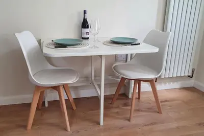 a white table with three chairs and a bottle of wine at Self-contained annex with private entrance, double bed, kitchen, bathroom, free car park - Near Cambridge, Duxford Air Museum and Addenbrooke's Hospital in Cambridge